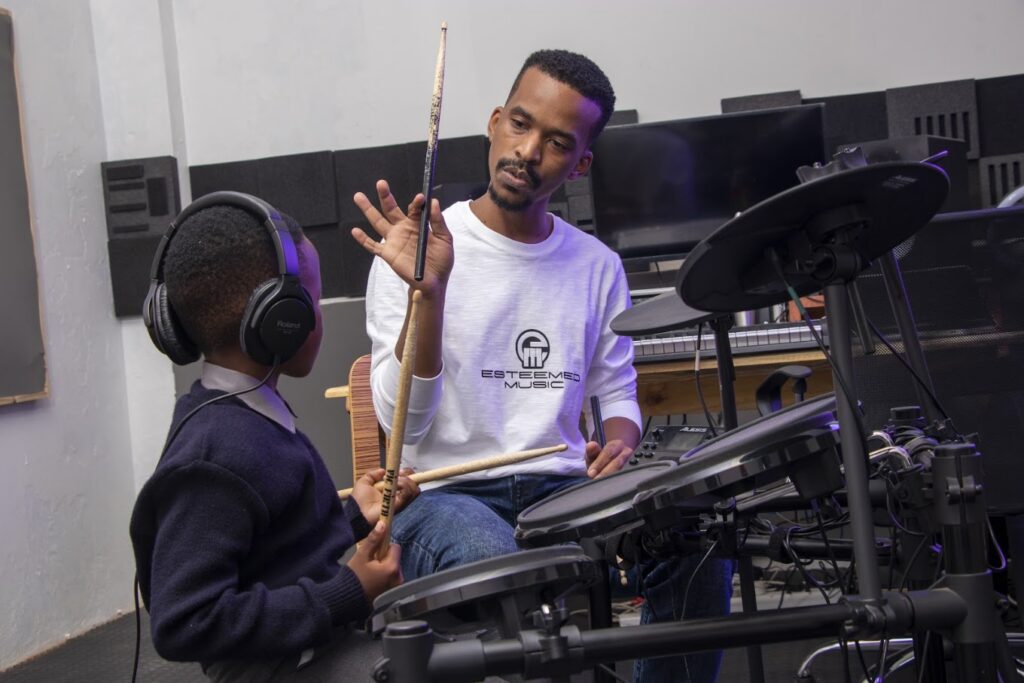 Thapelo Mofokeng, Founder and CEO of Esteemed Music, teaching a young student drums